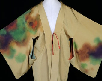 Könnte beinhalten: Ein beiger Kimono mit einem Bindeverschluss und einem farbenfrohen abstrakten Muster an den Ärmeln. Das Muster ist eine Mischung aus Grün, Lila, Orange und Braun.