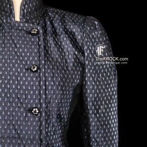 May include: A black and blue patterned jacket with a mandarin collar and decorative buttons. TheFROCK.com and www.CTMadrigal.com are printed on the jacket.