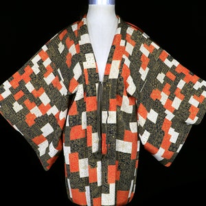 May include: A black, white and orange patterned Japanese kimono with a black zipper and a black tassel.