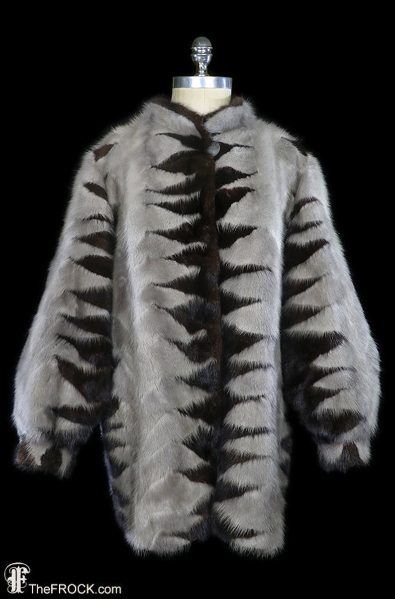May include: A gray and brown fur jacket with a tiger stripe pattern. The jacket has a button closure and long sleeves.