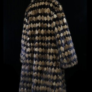 May include: A long, brown and black fur coat with a geometric pattern. The coat is made of mink fur and has a high collar.