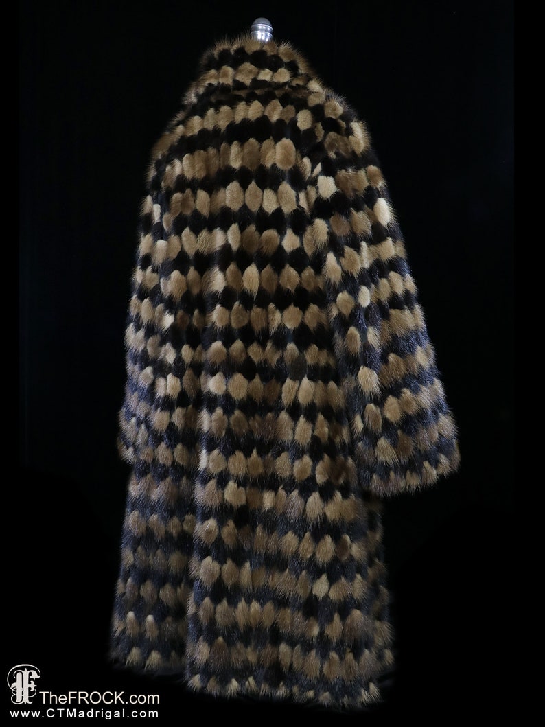 May include: A long, brown and black fur coat with a geometric pattern. The coat is made of mink fur and has a high collar.