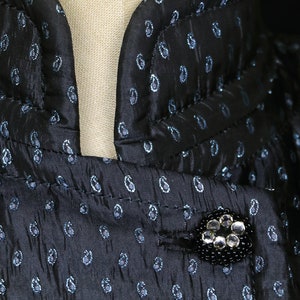 May include: A black and blue paisley patterned fabric with a black button adorned with clear rhinestones.