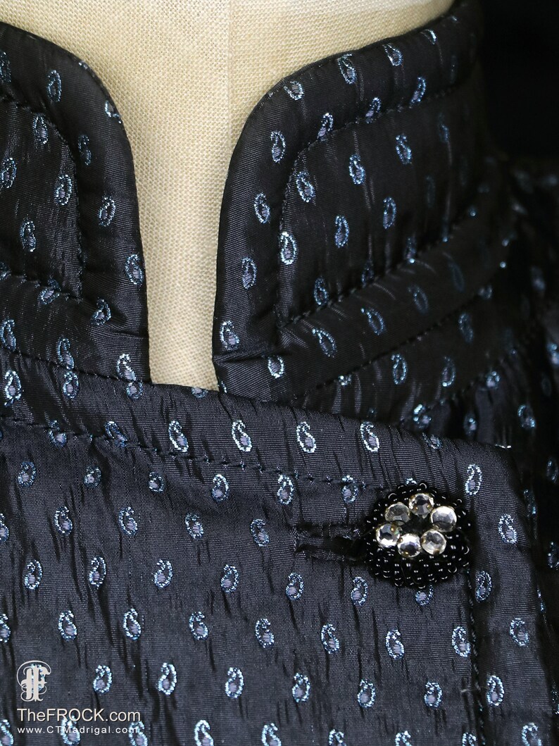 May include: A black and blue paisley patterned fabric with a black button adorned with clear rhinestones.