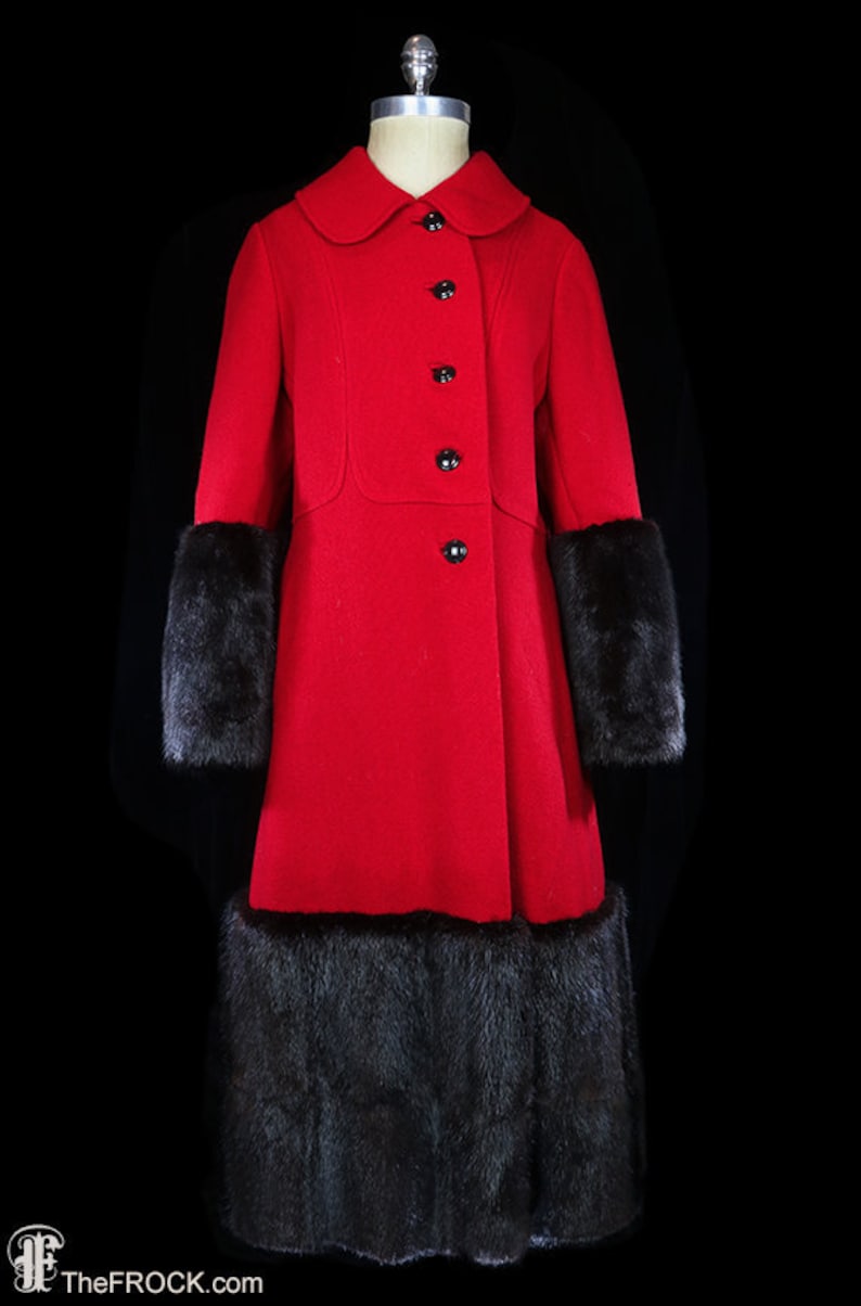 May include: A red wool coat with a black fur trim around the cuffs and hem. The coat has a Peter Pan collar and a row of black buttons down the front.