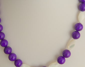 May include: A purple and white beaded necklace with round purple beads and oval white beads.