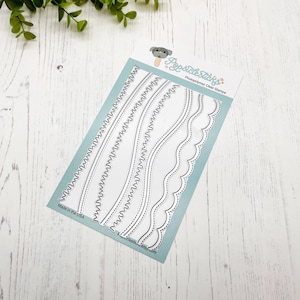 May include: A sheet of clear photopolymer stamps featuring a variety of wavy and scalloped border designs. The sheet is labeled "Popsicle Sticks Photopolymer Clear Stamps" and "Made in the USA".