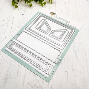 May include: A silver metal die-cutting template for creating a box with a window. The template is made up of five pieces, including a base, a lid, a window, and two side panels. The template is designed to be used with a die-cutting machine.