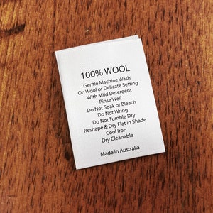 May include: White care label with black text that reads "100% WOOL" and instructions for washing, drying, and ironing wool garments. The label also states "Made in Australia."