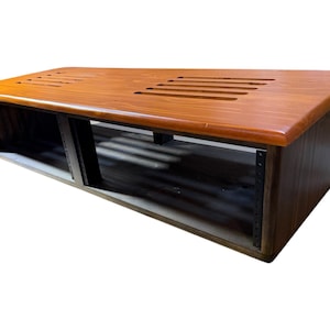 May include: A rectangular wooden equipment rack with a polished light brown top surface featuring two sets of parallel ventilation slots. The frame is constructed from dark wood with black metal vertical rails containing pre-drilled mounting holes.