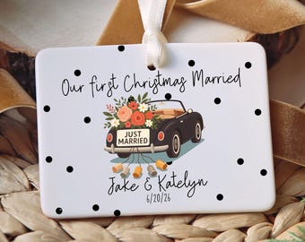May include: A rectangular white ceramic ornament with black polka dots, featuring a black convertible car illustration with flowers, a Just Married sign, and hanging cans. Text reads Our first Christmas Married, Jake & Katelyn, 6/20/26.