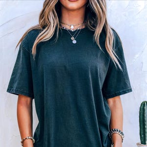 K&ouml;nnte beinhalten: Ein kurz&auml;rmeliges T-Shirt mit Rundhalsausschnitt in einem dunklen, verwaschenen Anthrazitgrau. Der Stoff hat eine leicht verblasste, vintage-inspirierte Textur. Das Wort "pepper" ist in kleiner, schwarzer Schrift auf der linken Seite gedruckt.