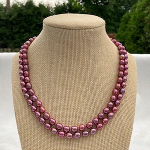 May include: A double strand pearl necklace with pink and purple iridescent pearls.