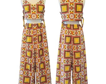 Peut inclure: Un ensemble deux pièces composé d'un haut court sans manches et d'un pantalon large. L'ensemble présente un motif géométrique répétitif en jaune, rouge, noir et blanc. Le haut court possède des liens latéraux et le pantalon une taille élastique.