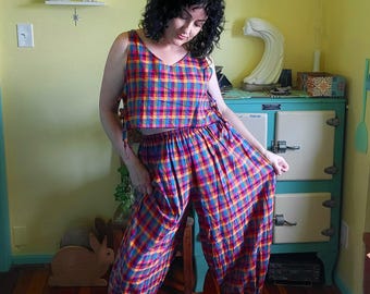 Peut inclure: Un ensemble deux pièces composé d'un haut court sans manches et d'un pantalon ample assorti. Les deux pièces présentent un motif à carreaux vif dans des tons de rouge, jaune, bleu et vert. Le haut possède des liens latéraux et le pantalon une taille élastique.