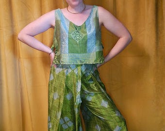 Peut inclure: Un ensemble deux pièces composé d'un haut court sans manches à col en V et d'un pantalon large. Le vêtement présente une palette de couleurs vert vif et bleu clair avec un motif géométrique répétitif et un emblème central sur la poitrine.