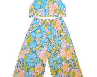 May include: A two-piece set consisting of a sleeveless crop top and wide-leg pants. Both pieces feature a vibrant floral pattern in shades of blue, pink, yellow, and green, accented by vertical light blue and orange stripes along the sides.