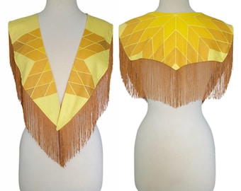 Peut inclure: Une capelette à motif géométrique jaune et doré avec une encolure en V profonde et de longues franges couleur beige le long des bords. Le vêtement présente un motif en forme d'étoile sur les panneaux avant et arrière, aux tons vifs.