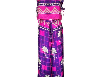 May include: A two-piece outfit featuring a sleeveless top and wide-leg pants. The set is patterned with a grid design in purple and pink, accented with white floral and geometric details. The top has tie closures, and the pants have a matching belt.