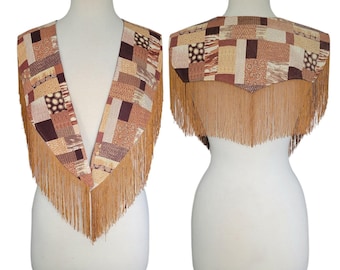 Peut inclure: Un gilet sans manches présentant un motif patchwork composé de divers motifs géométriques marron, beige et crème. Le vêtement possède un décolleté en V profond à l'avant et un ourlet pointu à l'arrière, avec de longues franges fines beige.