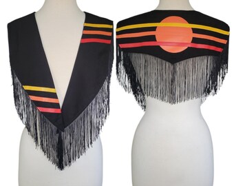 May include: A black shawl with long black fringe, featuring horizontal yellow, orange, and red stripes on the front panels and a large orange circular design on the back panel, displayed on a mannequin from both the front and back views.