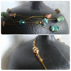 May include: A multi-strand necklace with gold wire and turquoise and blue stones. The necklace is displayed on a black mannequin.