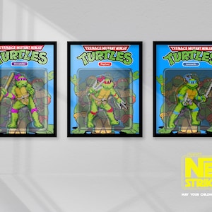May include: Three framed Teenage Mutant Ninja Turtles action figures. Each figure is in its original packaging, featuring a green turtle with different coloured masks and weapons. The frames are black, and the background is a light blue.