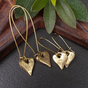 Pendientes de corazón dorados, largos o medianos, minimalistas y rústicos, con colgantes de metal en ganchos para la rodilla.