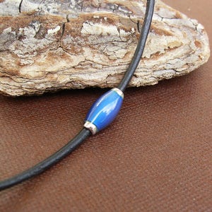 May include: A black leather cord necklace with a single blue glass bead.