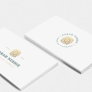May include: Two white business cards with a gold and teal logo. The logo is a circle with a stylized floral design inside. The text on the card reads "Sarah Neshie Est. 2000 Premium Flowers".