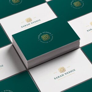 May include: A stack of green business cards with a gold logo featuring a stylized flower and the text "Sarah Neshie, Est. 2000, Premium Flowers".