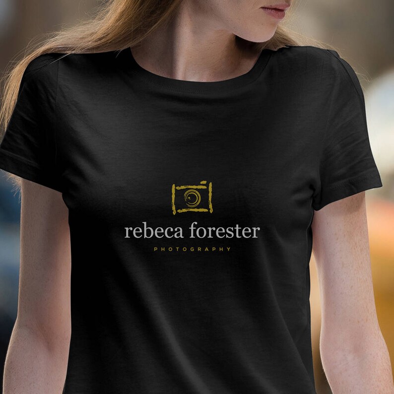 May include: Black t-shirt with a gold camera icon and the text "rebeca forester PHOTOGRAPHY" in white.