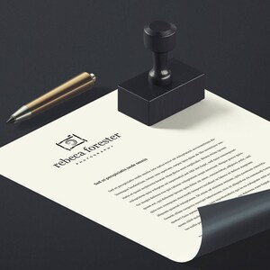 May include: A white sheet of paper with a black rubber stamp and a gold pen on a black surface. The paper has a logo for "rebecca forester photography" and the text "Sed ut perspiciatis unde omnis..."