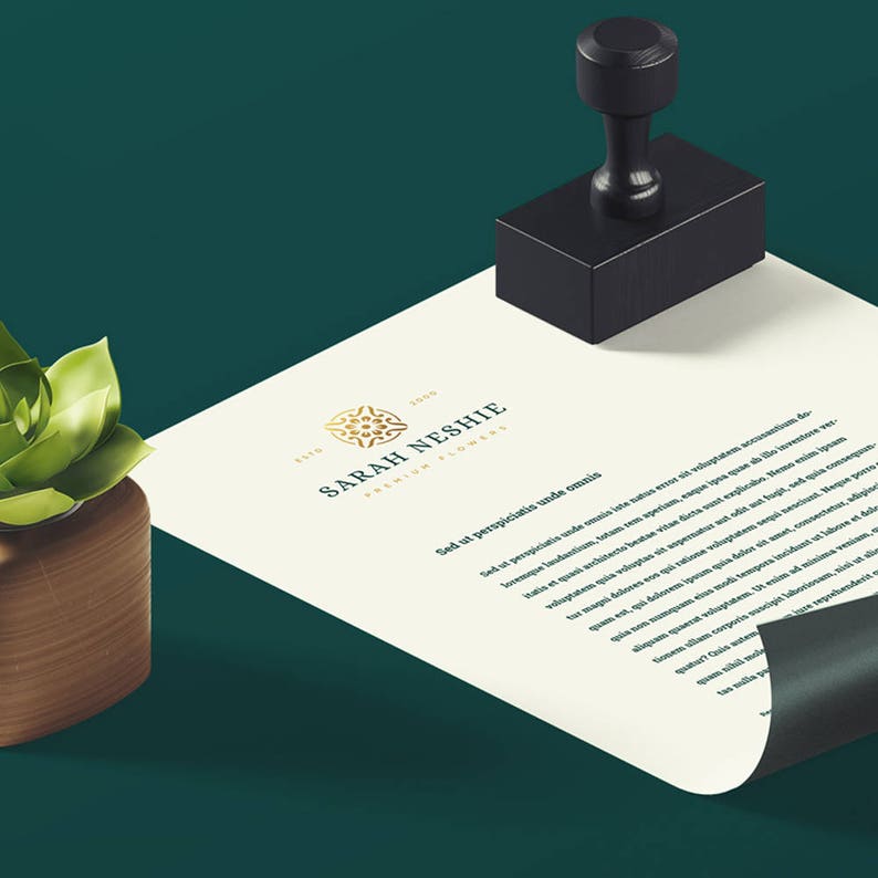 May include: A white sheet of paper with a gold logo that says "Sarah Neshie Premium Jewelry" and text in a serif font. The paper is on a green surface with a black rubber stamp.