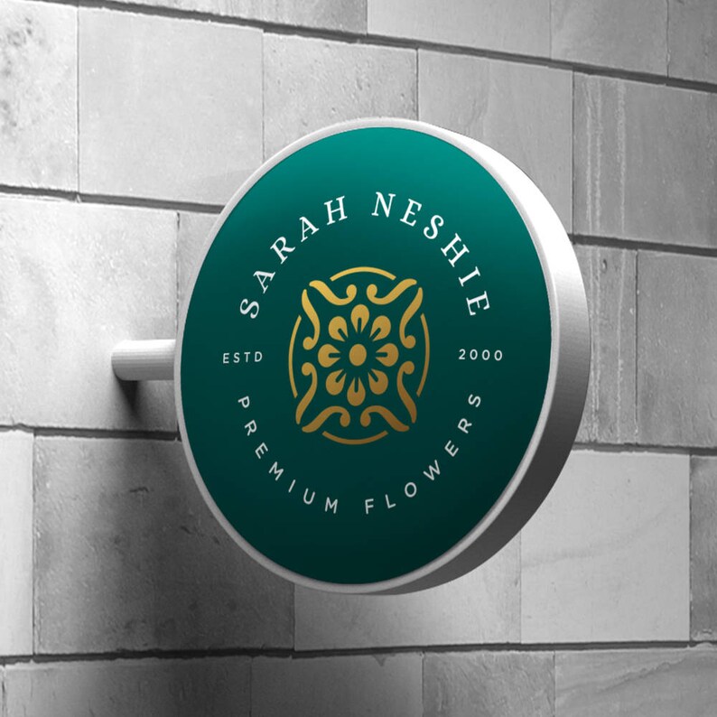 May include: A teal round sign with white lettering that reads "Sarah Neshie Premium Flowers Est. 2000". The sign has a gold floral design in the center.