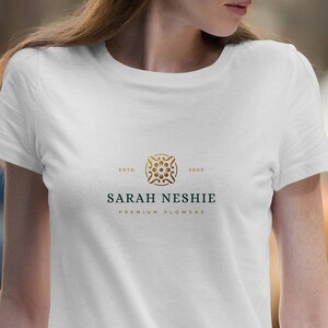May include: White t-shirt with a gold logo featuring a geometric design. The logo text reads "Sarah Neshie Premium Flowers" with "Estd 2000" above the logo.