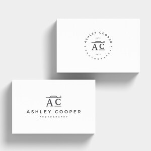 Puede incluir: Dos tarjetas de visita blancas con un logotipo de fotograf&iacute;a minimalista. El logotipo presenta las iniciales "AC" con un icono de c&aacute;mara y el nombre "Ashley Cooper Photography". Una tarjeta tiene un dise&ntilde;o de logotipo circular.