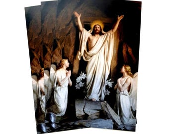 May include: A religious image depicting the resurrection of Jesus Christ. He stands in a cave with two angels kneeling before him. The image is painted in a realistic style with warm colours.