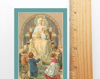 Puede incluir: Una impresión religiosa vintage que representa a la Virgen María y al niño Jesús. La imagen muestra a María sentada en un trono con una corona, sosteniendo a Jesús en sus brazos. Varios niños están arrodillados alrededor del trono, mirando a María y a Jesús. La impresión está enmarcada con un borde azul claro.
