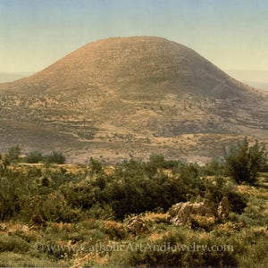 Puede incluir: Una vista panorámica de una gran colina redondeada con una superficie cubierta de hierba y marrón. La colina está rodeada de un paisaje de colinas y árboles más pequeños.
