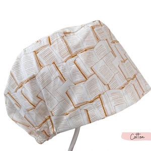 May include: A white cotton sun hat featuring a repeating pattern of open books in shades of brown. The hat is designed with a rounded crown and a brim, perfect for sun protection. The word "Cotton" is written in a pink rectangle.