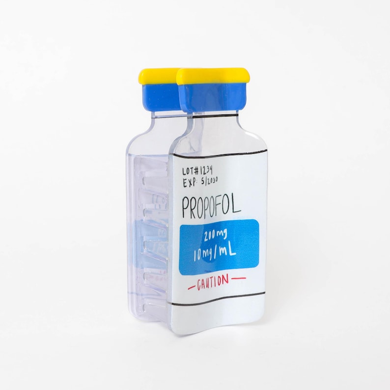 May include: A clear plastic bottle with a yellow and blue cap, featuring a white label with black text reading LOT#1234, EXP: 5/2030, PROPOFOL, 200mg, 10mg/mL, and the word CAUTION in red. The bottle has a flat, rectangular shape with rounded corners.