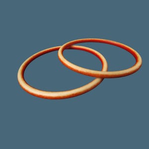 May include: Two orange-colored, circular bangles are interlocked against a muted teal background. The bangles have a textured appearance, with a gradient of color from a lighter orange to a darker, reddish-orange.