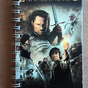 May include: Spiral-bound notebook featuring the movie poster for "The Lord of the Rings: The Return of the King." The cover displays a collage of characters and the film's title. Includes a quote: "Visually one of the most amazing achievements ever captured on film."