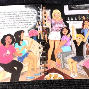 May include: An illustrated book spread depicts a group of people, including a blonde woman in a striped shirt and white shorts, surrounded by other people. The text on the page describes sharing with fans.