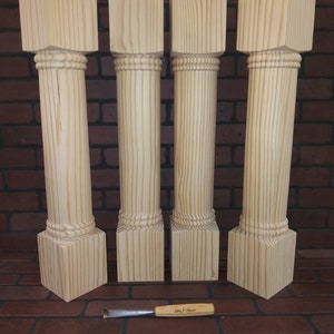 May include: Four unfinished wooden columns with a decorative bead molding. The columns are approximately 12 inches tall and 4 inches wide. A small wood carving tool is in the foreground.