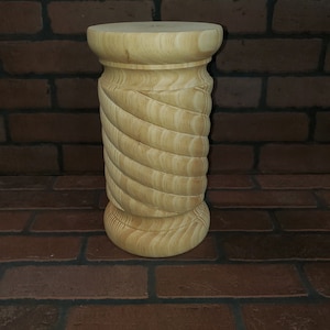 May include: A wooden stool with a spiral design. The stool is made of light wood and has a smooth finish.
