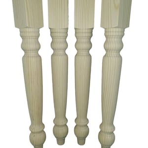 May include: Four unfinished wooden table legs with a turned design. The legs are hand-turned and have a square top.  "Genuinely hand turned art not mass produced copies" is written below the legs.