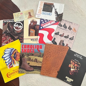 May include: A collection of vintage boot advertisements and catalogs. The items include catalogs for Double-H, Acme, Georgia, Walker, Carolina Shoes, and Durango Boot. The catalogs feature images of work boots and cowboy boots.