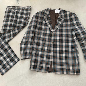 May include: A vintage plaid suit set featuring a blazer and matching pants. The suit has a brown, white, and teal plaid pattern. The blazer has a notched collar and button closure. The pants are flared.